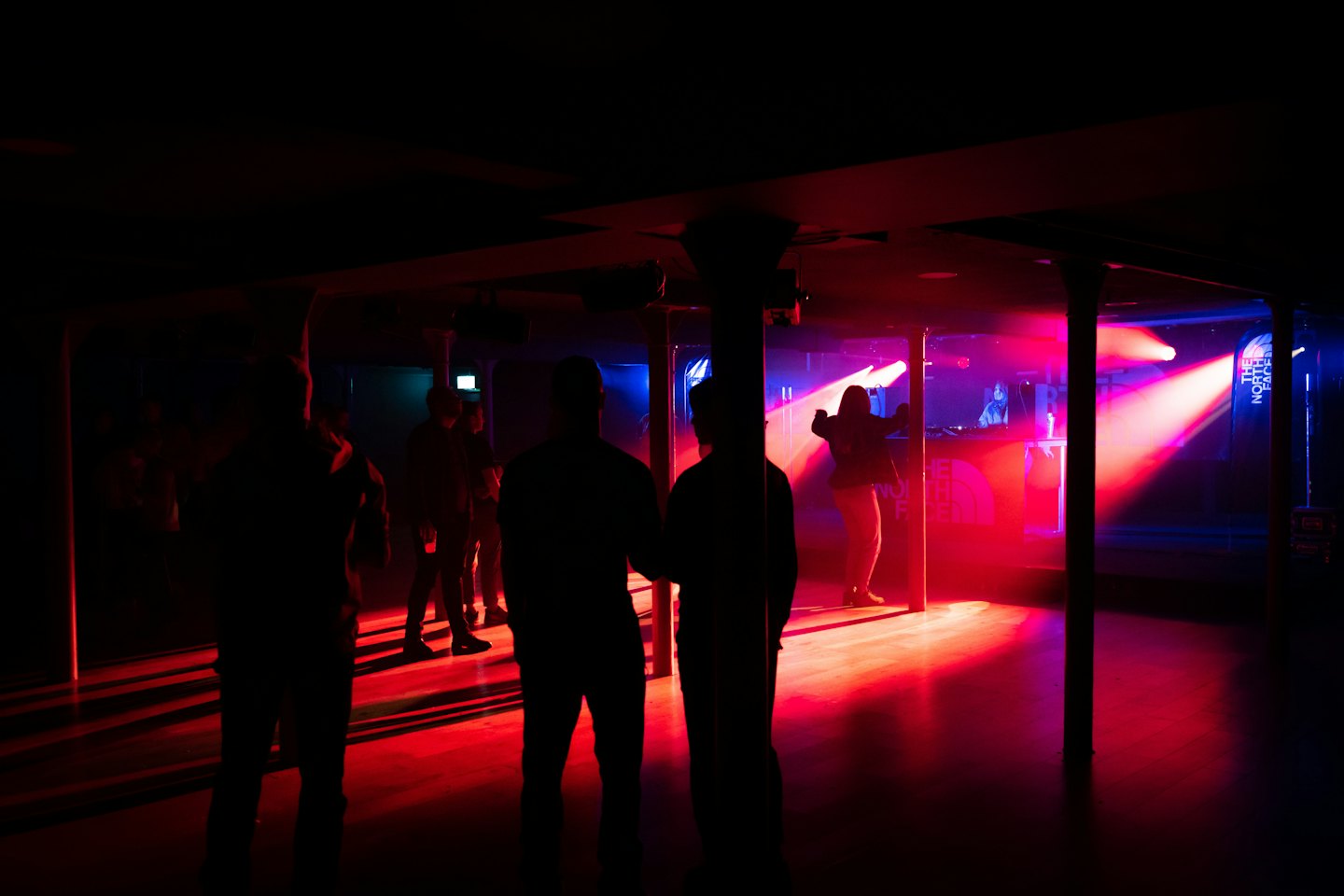 Mensen dansen in een nachtclub terwijl een DJ aan de console werkt.