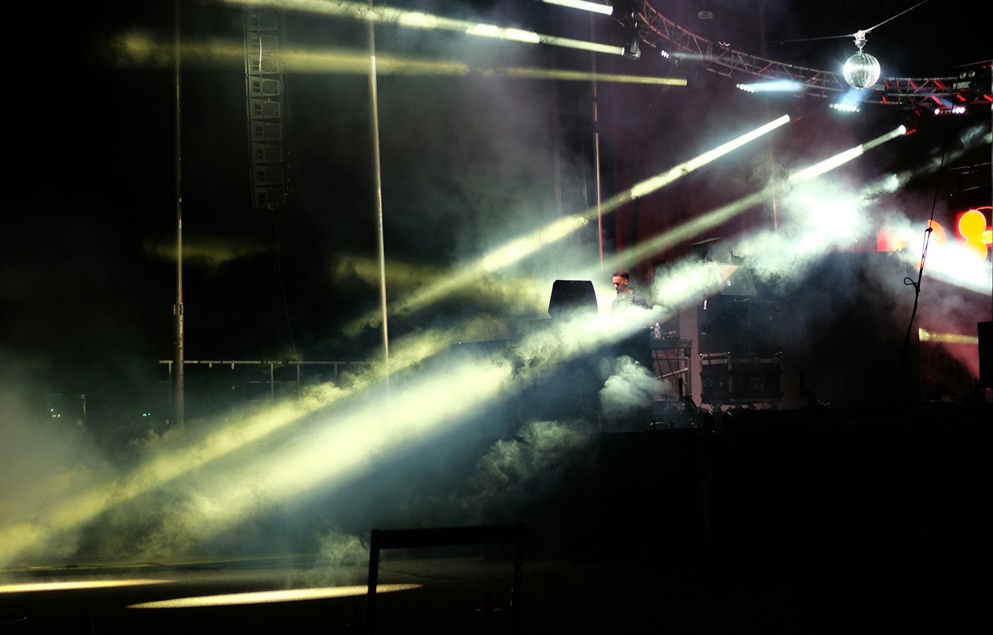 Een DJ mixt muziek op een podium vol rook.